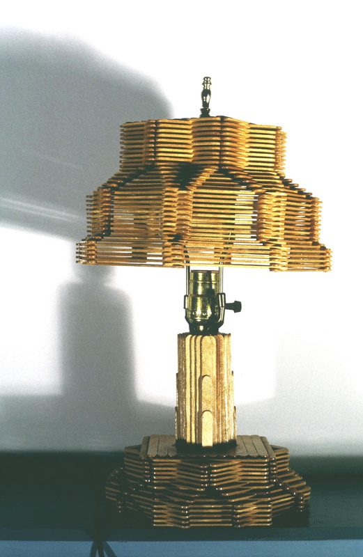 A lamp made out of wooden dowels and a light fixture.