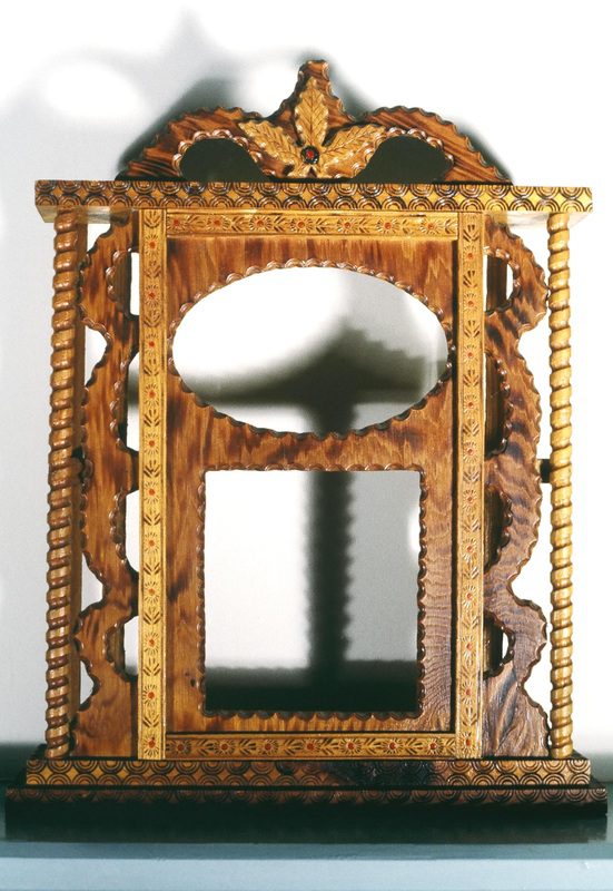 A mirror with a wooden frame and a decorative design.